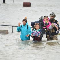 People wading through wasit deep flood
